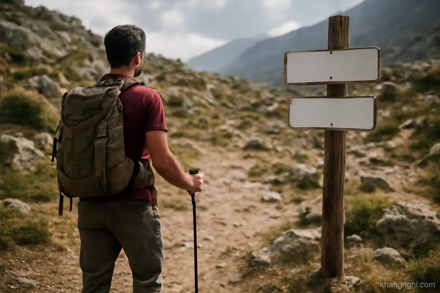 a hiker pausing where a marked trail ends and rougher ground begins beyond the last signpost
