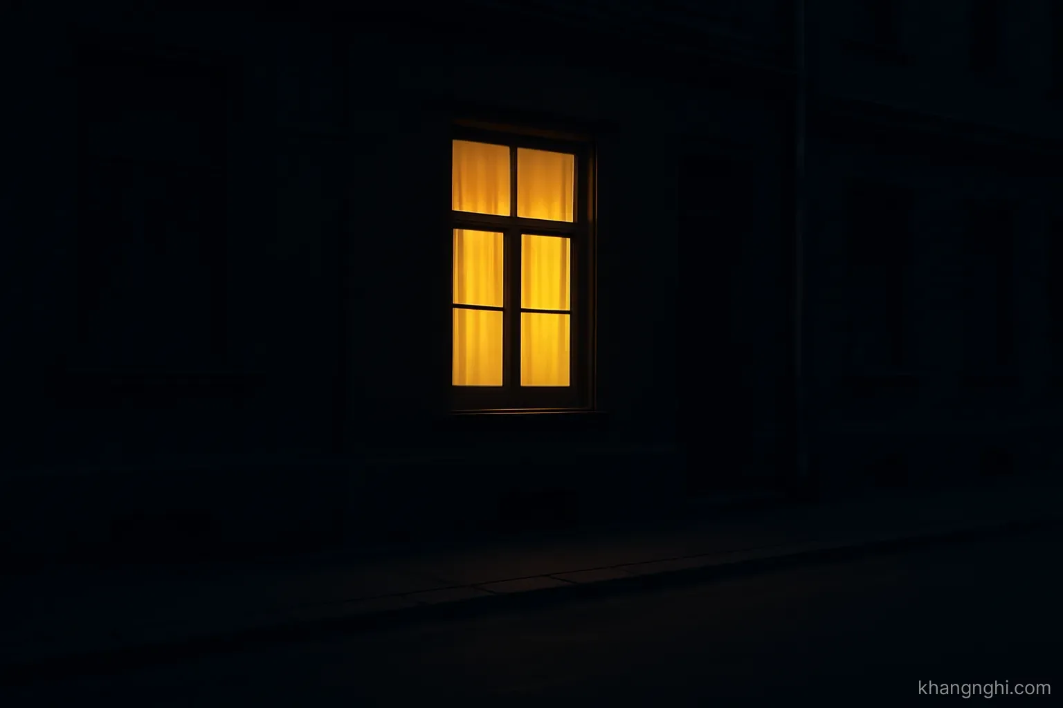 a lit window seen from a dark street, with the rest of the building in shadow on a quiet evening
